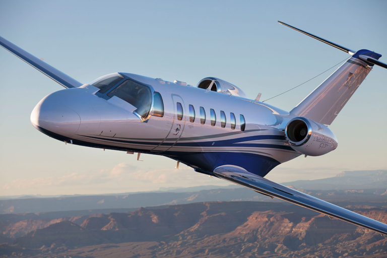 Cessna Citation CJ3 business jet in flight over mountains.