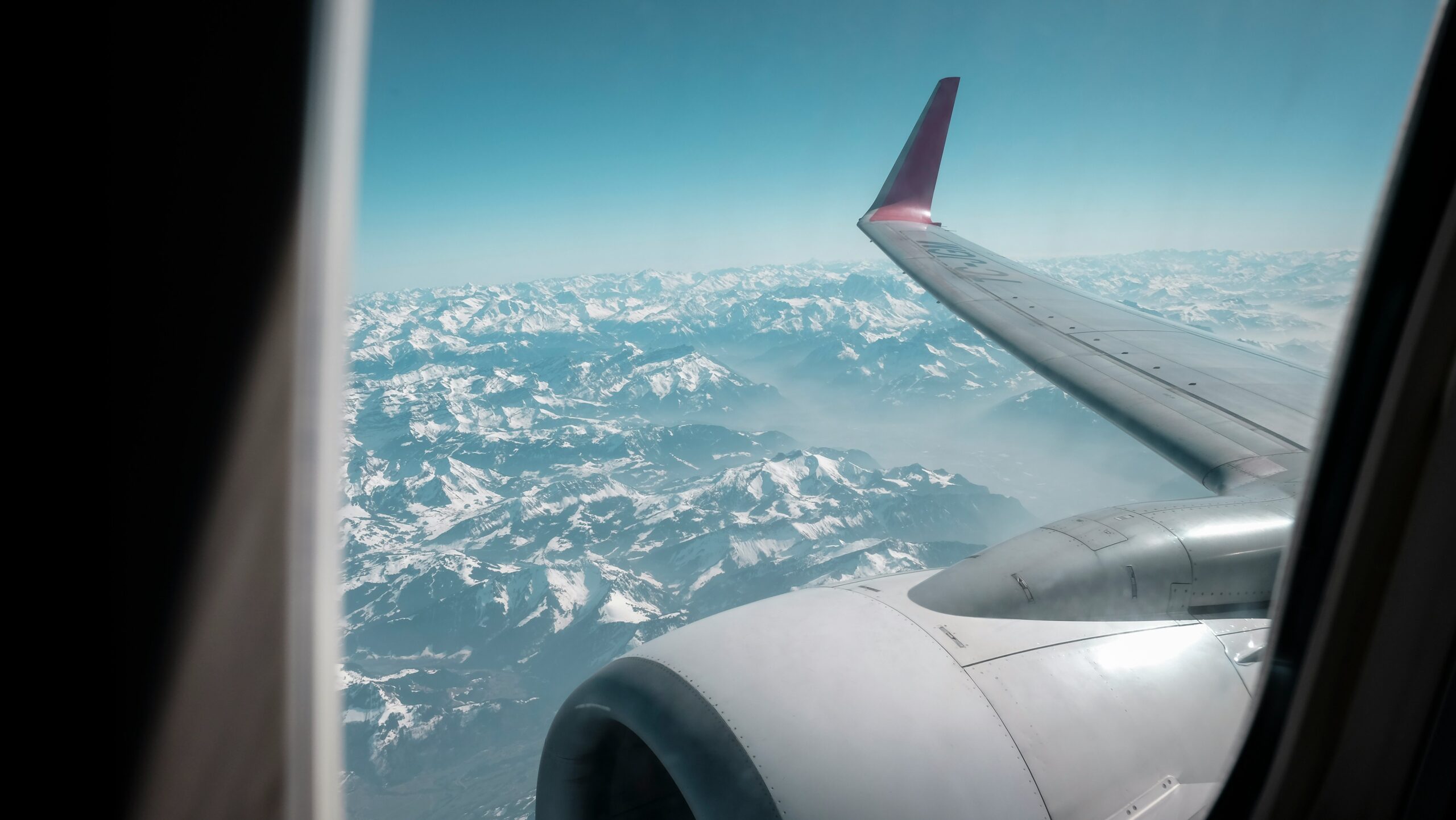 Aerial view of mountains through airplane window, highlighting aircraft insurance.